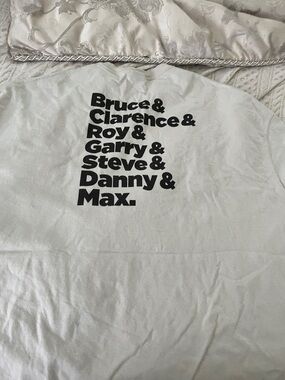 E street band in a sand. Band members on back of shirt
